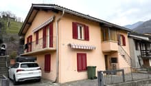 Two-story house, beige exterior, red shutters, balcony, car parked in front