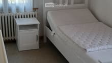 White bed frame, mattress, nightstand, wall decor with tropical beach scene