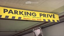 Yellow sign indicating a private parking area with height restrictions. Pipes are visible.