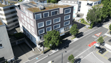 Aerial view of a multi-story building with several windows, a green roof, and an underground parking entrance.