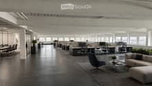 Modern office space with open-plan workstations, desks, chairs, and a lounge area featuring a sofa, coffee table, and chairs.