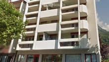 modern multi-story building, balconies, parking area, glass doors, red frames