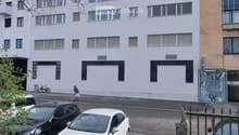 white 3 story building, windows, trees, sidewalk, cars parked, people walking, bicycles