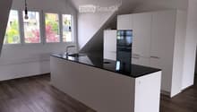 modern kitchen with island, black countertops, stainless steel sink, wooden floors, white cabinets, large windows