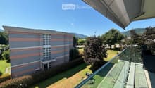 Apartment building, balcony with glass railing, landscaped garden, tree, lawn, distant mountain view