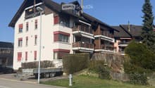 3 story apartment building, white and brown exterior, red shutters, balconies, street view