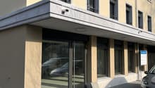 Modern building with glass facade, balcony, and parking area