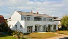 2 story house, white exterior, gray roof, large windows, balcony, garden, driveway