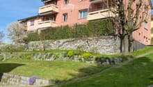 3 story house, pink exterior, multiple balconies, stone wall, green lawn, tree