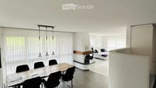 Dining room with a long wooden table, black chairs, white walls, white ceiling, fireplace, white curtains, and a white curved wall.