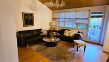living room with wooden floor, chandelier, black leather couches, coffee table, rug, picture frame, lamp, ottoman, potted plant, balcony