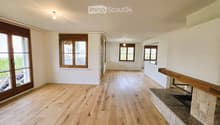 Empty room with hardwood floors, white walls, large windows, and a fireplace with a stone mantle.