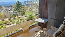 balcony with seating area, metal railing, table, chair, tile floor, view of town