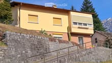 2 story house, yellow exterior, brown roof, stone wall, staircase, balcony, windows with shutters