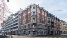 5 story building, red brick, white windows, balconies, awnings, street level shops