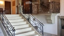 white marble stairs, wooden ceiling, black railings, wooden door, picture frame