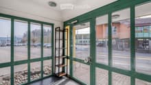Entrance hall with green glass walls, tiled floor, small shelf, and a view of the street outside