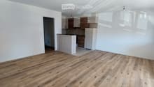 empty room, wooden floor, white walls, open door, kitchen area, cabinets, countertop, ceiling lights