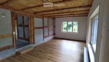 Unfurnished Room. Empty room with wooden ceiling, wooden flooring, and white walls. Two windows with wooden frames and a power outlet on the wall.