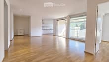 Unfurnished Room. Bright, unfurnished living space with wooden flooring, large windows, and a sliding glass door leading to a balcony.