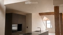Kitchen. Modern kitchen with a central island, stainless steel sink, faucet, built-in oven, and dark grey cabinets. Exposed wooden beams and a balcony overlook the space.