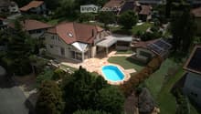 Aerial view of a residential area with multiple houses, a swimming pool, and well-maintained gardens.