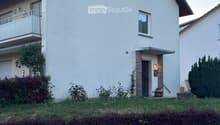 Two-story white house with a pitched roof, balcony, and small garden area.