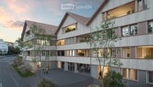 Modern multi-story residential building with a contemporary design, featuring large windows, balconies, and a mix of wood and concrete materials.