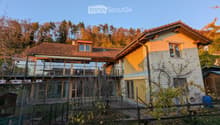 3 story house, yellow exterior, red tiles, large balcony, garden, forest backdrop