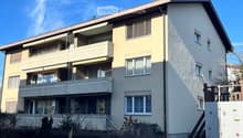 3-story apartment building, beige exterior, multiple balconies, clear windows, white railings