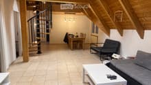 Modern living room with exposed wooden beams, a spiral staircase, a sofa, a coffee table, a dining table with chairs, and a futon.