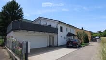Two-story house with white exterior, garage, balcony, and a parked car in front.