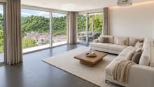 Modern living room with large windows offering a scenic view, featuring a white sectional sofa, wooden coffee table, and projector mounted on the wall.