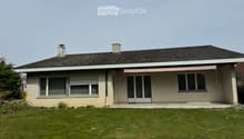 Single-story house with beige siding, dark tiled roof, multiple windows, and a covered entrance with a pink awning.