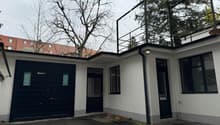 White house with garage, terrace on the top, black railings, black windows