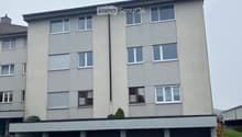 Four-story apartment building with multiple windows and a row of garages at the bottom.