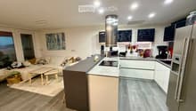 Modern open-plan living and kitchen area with a sofa, coffee table, kitchen island, and various appliances.