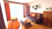 Living room with a grey sofa, orange cushions, a wooden coffee table, a floor lamp, and decorative plates on the wall.