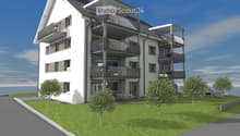 Modern multi-story residential building with balconies, surrounded by a well-maintained lawn and trees.