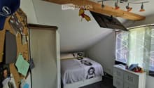 sloped ceiling, bed, bedside table, window, wardrobe, bulletin board, mounted television, pin cushion