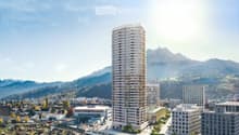 Building. A modern high-rise building stands prominently in the foreground, surrounded by smaller structures and a scenic mountainous backdrop.
