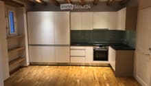 Modern kitchen with white cabinets, stainless steel oven, and wooden flooring.