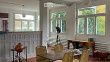 Bright, open room with large windows, wooden table, four chairs, globe on a stand, and a desk with office chair.