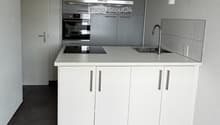 Modern kitchen with white cabinets, stainless steel appliances, and a central island with a sink and faucet.