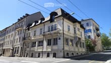 A multi-story residential building with classic architecture, featuring balconies, large windows, and ornate stonework.