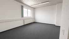 Empty room with white walls, grey carpet, a window with a green curtain, and a radiator below the window.
