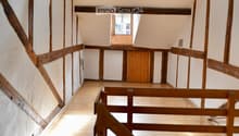 Exposed wooden beams, white walls, wooden staircase, wooden floor, small window