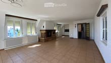 Bright hallway with tiled floor, large windows, fireplace, and open doorway leading to another room.
