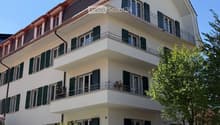 3 story white house, green shutters, balconies, red roof, garden, street view