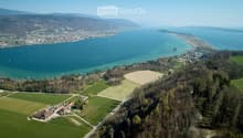 Aerial view of a rural area with fields, a small farm, and a large body of water in the background.